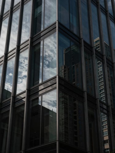 Severe architectural detail of a modern glass-and-steel skyscraper facade in Madrid, sharp geometric angles, dramatic chiaroscuro with deep shadows and cool daylight reflecting off the dark tinted glass, high-contrast luxury aesthetic.