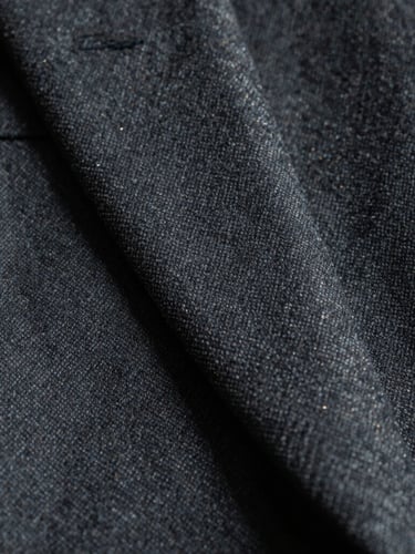 Severe cinematic macro shot of tailored dark grey wool suit fabric, sharp focus on the weave, deep shadows, cool daylight, gold thread detail
