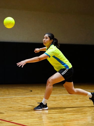 Dynamic low-angle action shot of an agile dodgeball player mid-throw in a high-contrast indoor sports hall, intense saturated colors, dramatic shadows, neon yellow ball in focus, 85mm lens, shallow depth of field