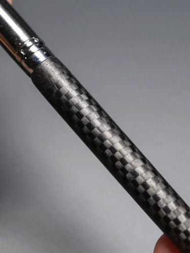 Sharp studio macro photography, close-up of a stylist's hand gripping a sleek charcoal carbon fiber brush handle, high-contrast directional light, matte metallic background