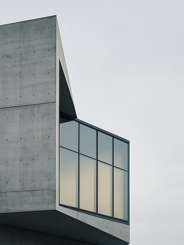 Minimalist modern Swiss concrete and glass architecture facade, sharp angles, soft overcast daylight, clean lines, generous negative space on the right