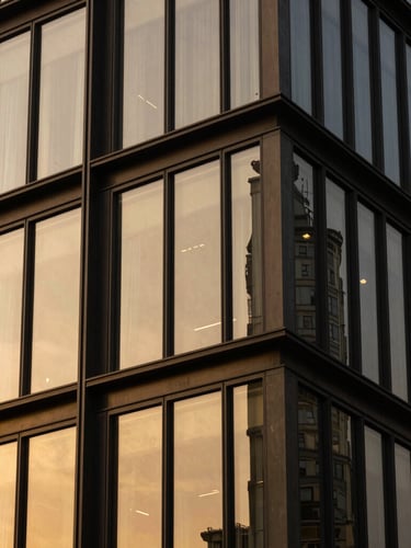 Close-up architectural detail of a modern luxury building facade, sharp angles, dark steel and gold-tinted glass under dramatic high-contrast lighting