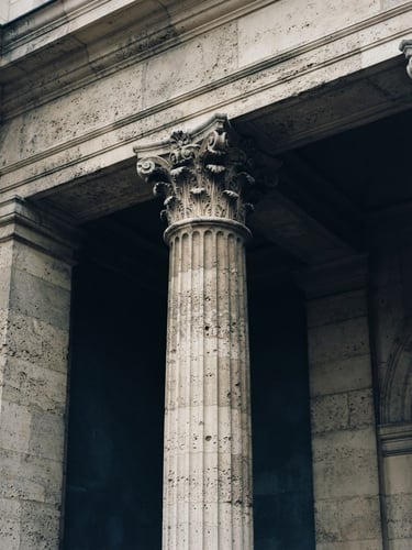 Close-up of a classic stone facade with architectural columns, soft overcast daylight, deep navy shadows, timeless editorial photography, 35mm film style