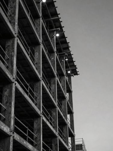 Extreme close-up of a Calgary construction site facade at dusk, steel beams and scaffolding dominating the left edge, a sliver of cold grey sky visible to the right, clinical overhead industrial lighting, hard shadows, high contrast monochrome
