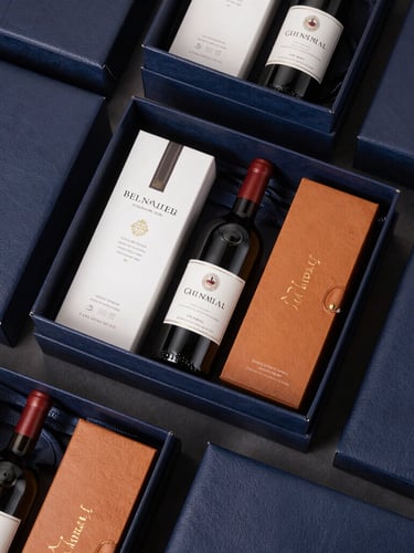 Overhead flat-lay of a meticulously arranged luxury gift hamper with leather textures, premium wine bottle, and elegant packaging materials, crisp studio lighting, 50mm