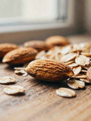 Macro close-up of raw almonds and whole rolled oats on a rustic wooden surface, warm side-lighting from a window, soft shadows, 35mm film style