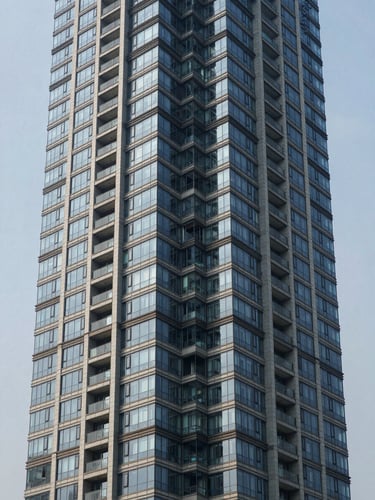 Straight-on architectural elevation of a glass-clad high-rise residential tower on Dwarka Expressway, overcast natural daylight, no human presence, clean facade detail