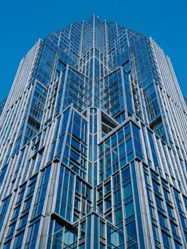 Wide-angle architectural detail of a modern financial district skyscraper with sharp geometric lines, bright high-contrast daylight, cobalt blue and cool grey tones, 35mm