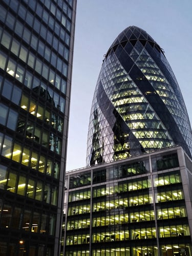 Wide-angle architectural shot of London financial district buildings with sharp office lighting and deep slate shadows