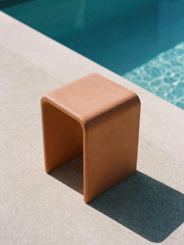 Low-angle architectural shot of a terracotta monobloc stool on concrete poolside, harsh direct midday sun casting sharp graphic shadow, matte polymer texture, 35mm film.