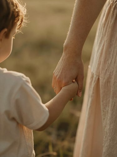 Intimate close-up of a mother holding her child's hand, soft diffused golden light, warm earthy tones, shallow depth of field.