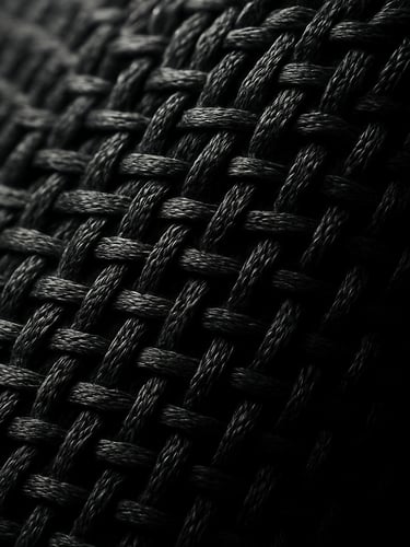 Extreme macro close-up of a high-tech athletic fabric weave, charcoal grey fibers, dramatic side lighting, sharp texture detail, 35mm lens