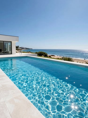 Bright architectural photography of a modern concrete pool integrated with coastal home architecture, sparkling clear blue water under sunny daylight, rich blue and white tones, wide-angle lens.