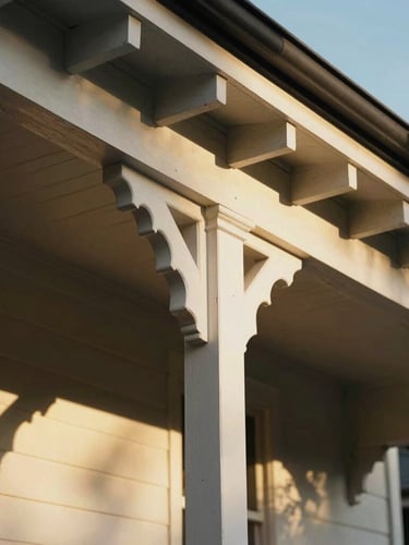 Tight architectural crop of a Brisbane Queenslander home, showing detailed timber veranda brackets, deep shadows, warm golden hour light reflecting off white timber.