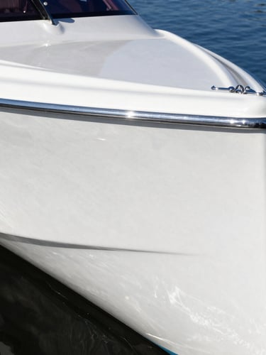 Extreme close-up of a gleaming white fiberglass hull reflecting deep blue lake water under bright midday sun, water-beading on a freshly coated ceramic surface, 35mm marine photography.