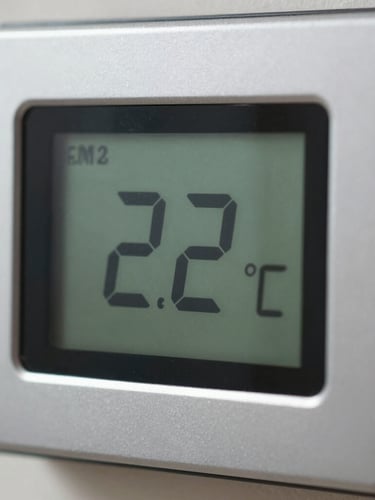 Macro close-up of a digital climate control interface showing a steady 22 degrees Celsius reading, clean metallic housing, and sharp focus.