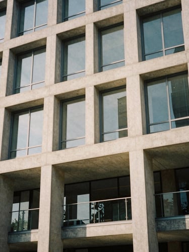 Architectural detail of a modern concrete and glass commercial building facade, warm natural low-contrast daylight, medium format film