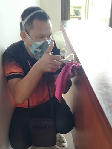 Professional exterminator wearing a mask and using a spray gun for indoor pest control treatment.