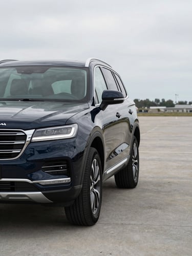 Wide shot framed from driver's side, a dark navy SUV at 3/4 front angle on a clean concrete lot under neutral overcast daylight, no people, trim detail and grille sharp in foreground, expansive negative space to the right