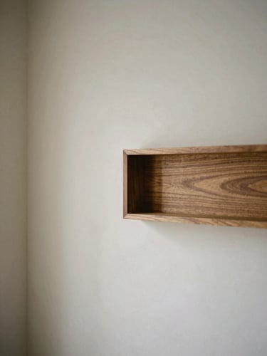 Detail shot of custom walnut joinery meeting a hand-applied plaster wall, soft side-lighting highlighting the rich texture of the plaster and the precise wood grain, medium format film.
