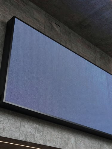 Low-angle architectural shot of a massive LED screen integrated into a concrete corporate lobby wall, high-contrast structural lighting, cool metallic grays.