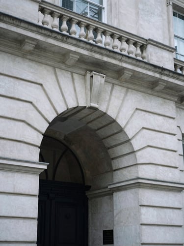 Close-up architectural detail of a classic Portland stone archway in Mayfair, soft overcast London daylight, desaturated cool tones, elegant shadows, 35mm film.