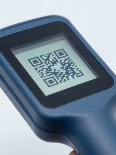 Macro shot of a handheld logistics scanner displaying a QR code on a screen, cool blue and slate tones, sharp focus