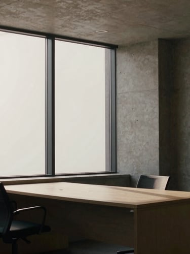 Quiet modern architectural office environment with concrete columns, low-key side lighting casting long shadows across a minimalist desk, editorial film photography.