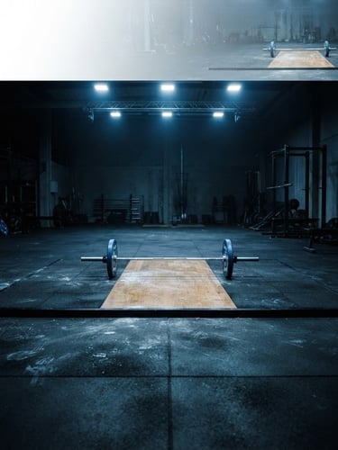 Wide panoramic shot of an empty Olympic weightlifting platform under focused overhead spotlights, barbell centered, chalk dust visible on the dark floor, high contrast cool tones.