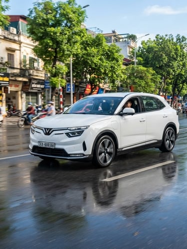 Modern electric SUV driving on a clean urban boulevard in Hanoi, bright morning daylight, reflections on wet asphalt, sharp focus, 50mm lens