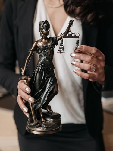 Abogada sosteniendo una estatua de la justicia con balanza, en un entorno profesional.