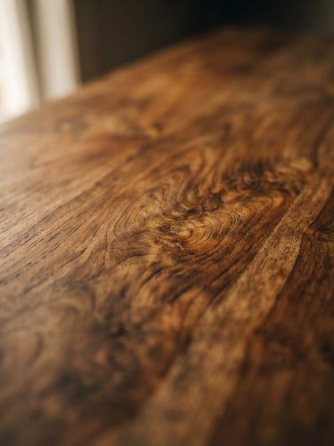 Editorial close-up of premium warm teak wood grain with soft natural window light, shallow depth of field, 35mm