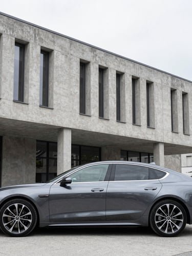 Sleek dark metallic executive sedan parked in front of modern concrete architecture in Ljubljana, bright overcast daylight, cool desaturated tones, sharp focus, 35mm lens