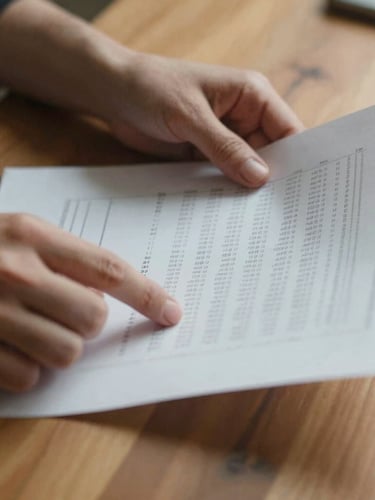 Close-up of hands reviewing clear financial documents on a warm wooden table, soft daylight, 35mm photography, authentic.