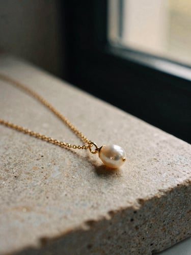 Detailed macro shot of a delicate gold chain necklace with a pearl pendant on stone, warm lighting, 35mm film.