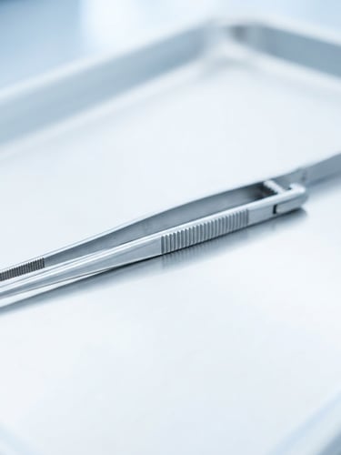 Sharp macro product shot of sterile surgical instruments, bright high-key product photography, sterile clinical studio lighting, cool white and blue tones, sharp macro focus on steel forceps