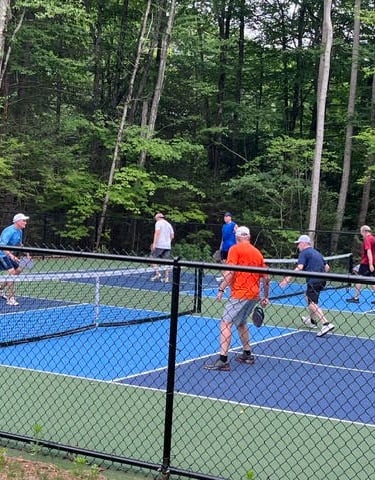 Men playing pickleball doubles on an outdoor blue and green pickleball court