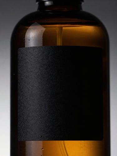 Sleek amber glass bottle with minimalist black label, dramatic high-contrast side lighting, sharp details, luxury editorial style