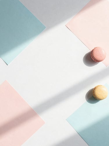 Minimalist abstract flat-lay of geometric pastel paper shapes casting soft morning shadows on a clean white desk, 35mm lens