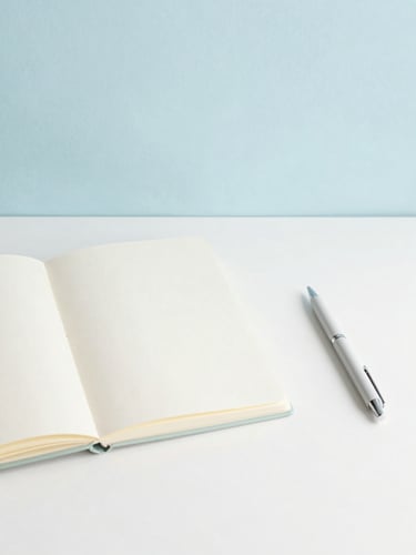 Minimalist flat-lay of a clean workspace desk with soft natural morning light, pastel sky blue and cream tones, a single open notebook and elegant pen, generous negative space