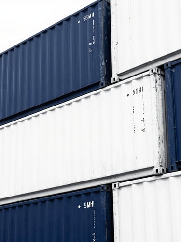 High-contrast duotone photograph of stacked shipping containers in Port Klang, sharp architectural angles, deep navy blue and stark white tones, 35mm
