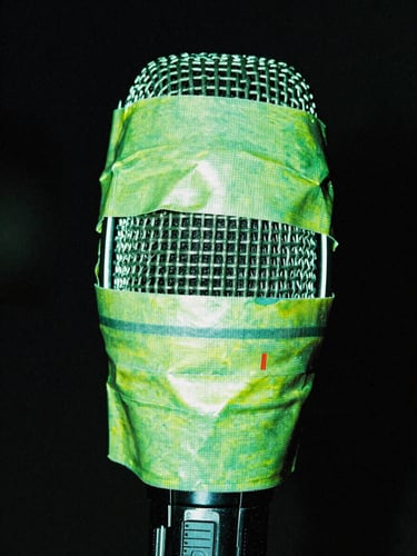 Microphone covered in duct tape, extreme close-up, harsh direct flash, neon green highlights, portrait aspect.