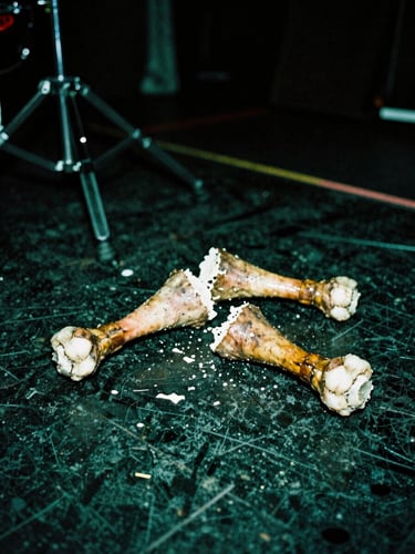 Broken drumsticks lying on a sweat-stained stage, harsh direct flash, portrait aspect.