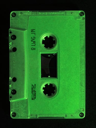 Distorted analog audio cassette tape unspooling, high-contrast green and black, portrait aspect.