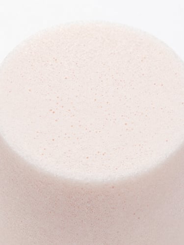 Macro close-up showing the fine, high-density cell structure of a latex-free hydrophilic polyurethane cosmetic sponge, bright clean studio lighting