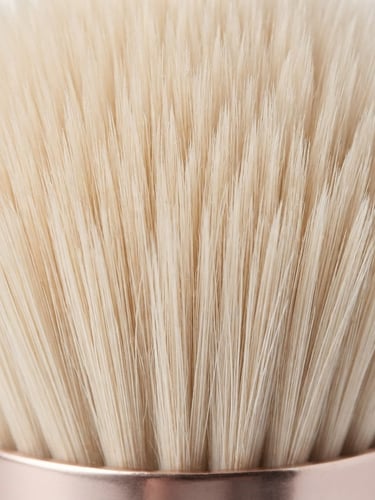 Macro close-up of premium synthetic makeup brush bristles, highlighting ultra-fine tip alignment and dense packing, bright high-key studio lighting, minimalist white background