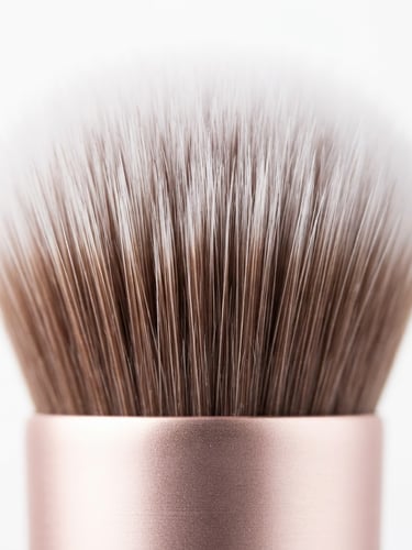 Macro close-up of premium synthetic makeup brush bristles, soft rose-gold ferrule, bright high-key studio lighting, minimalist white background