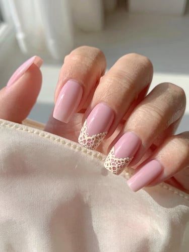Macro shot of hand-painted pastel pink press-on nails with delicate cream lace details held against a vintage silk slip, soft morning sunlight, shallow depth of field