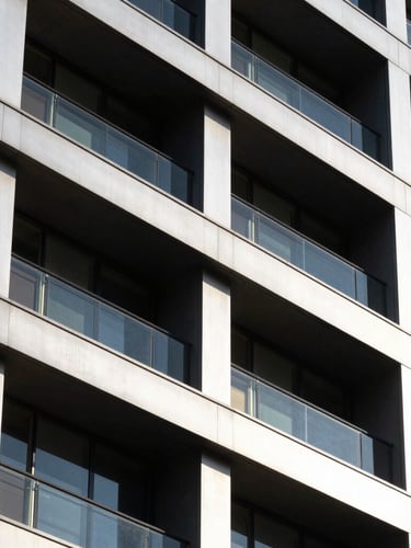 High-contrast architectural portrait of a newly completed commercial building facade, sharp geometric shadows, clean steel and glass, bright daylight.