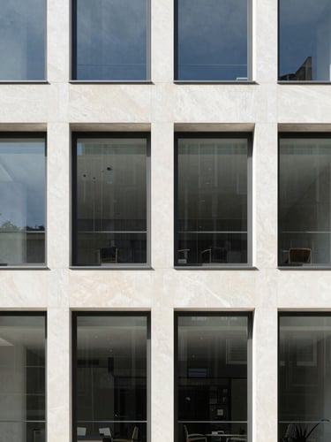 Bright natural daylight hitting a modern limestone building facade with clean architectural lines, sharp focus, minimalist composition, 35mm lens